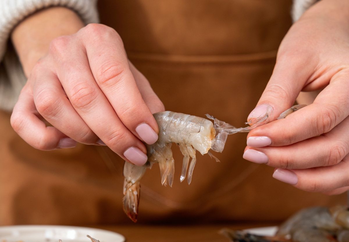 Cocinera limpiando camarones con las manos