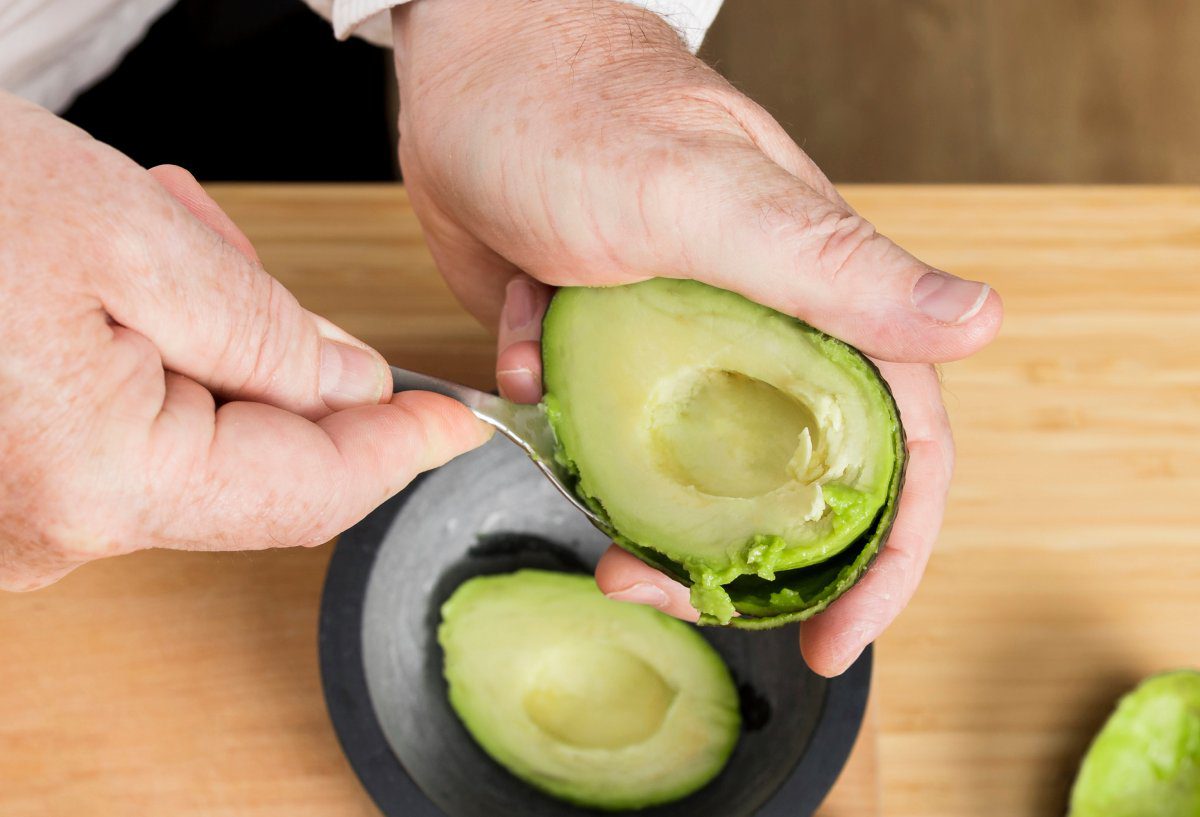 Persona cortando aguacate, tambien conocido como palta